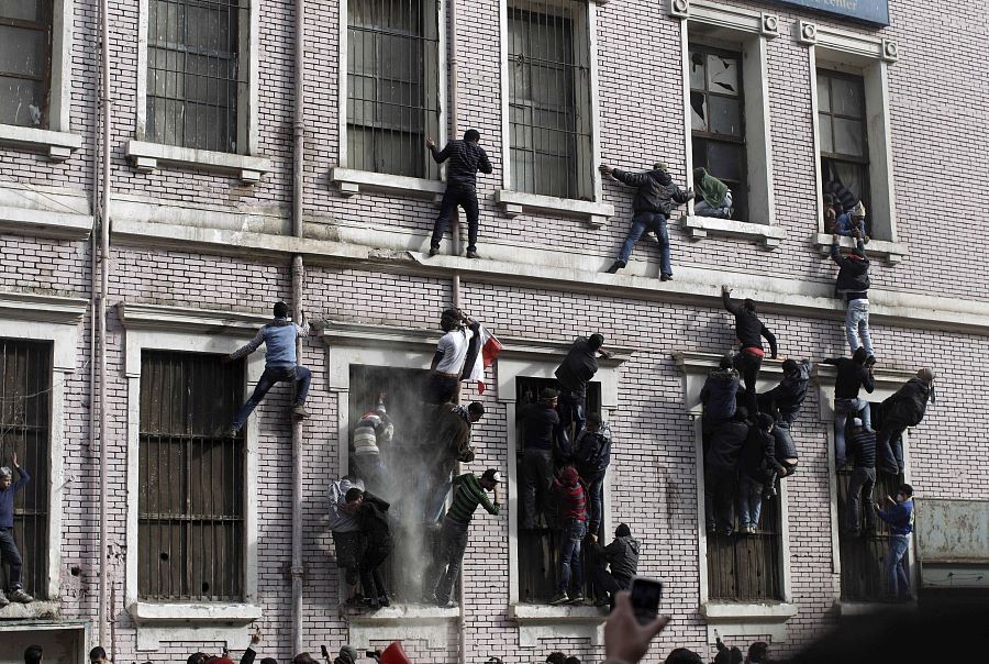 Egyptian protestors climb the exterior of a building that caught fire during clashes with security forces near the Interior Ministry in Cairo, Egypt, today. Pic: AP