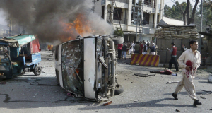 An injured victim walks away from a burning vehicle at the site of suicide bombing in Saidu Sharif, a town in Pakistans Swat Valley.