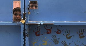 Palestinian children look through slots in a door during a visit of Foreign Minister Micheál Martin at an aid distribution center in Rafah, southern Gaza Strip, today. Pic: AP