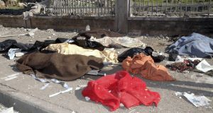 In this photo released by the Syrian official news agency SANA, covered dead bodies are seen in front of a Syrian military intelligence building in the northern city of Aleppo