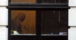 A forensics officer is seen through a window in a building in Mansfield Street, London, England, today. Pic: PA
